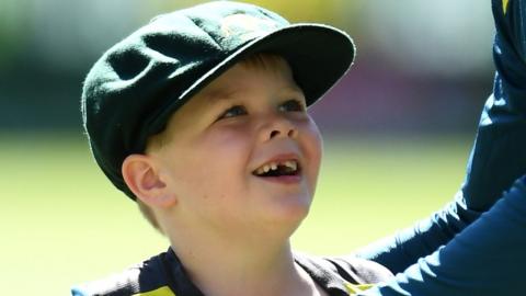 Archie Schiller wears the baggy green cap and smiles