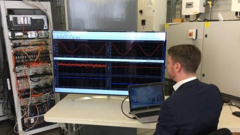 Man looking at electricity graphs on screen