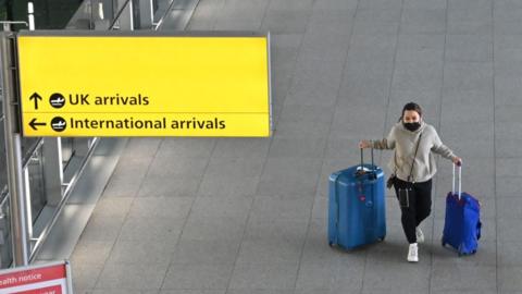 Woman travels through Heathrow airport wearing a mask