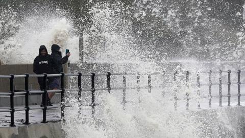 Pepple take pictures as waves crash over pier in Folkestone on 2 November