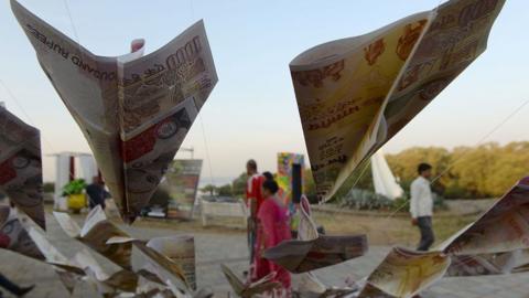 People walk past replica prints of the demonetised 500 and 1000 rupee notes as part of a street art exhibition in Mumbai