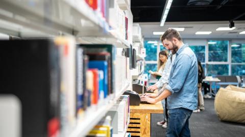 People looking at books on the shelf of a library