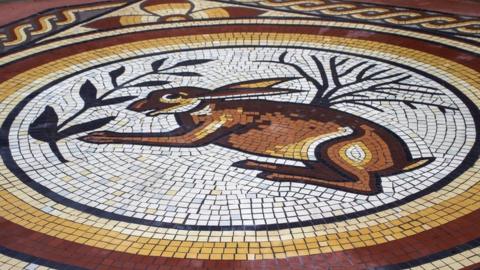 Image of the hare mosaic in Cirencester. It shows a hare in the centre, with yellow and red rings around it