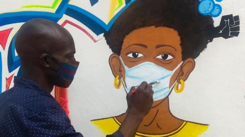 Congolese artist Chris Shongo paints a coronavirus-themed mural on the outside wall of the Academie des Beaux-Arts in Kinshasa, in June 2020.
