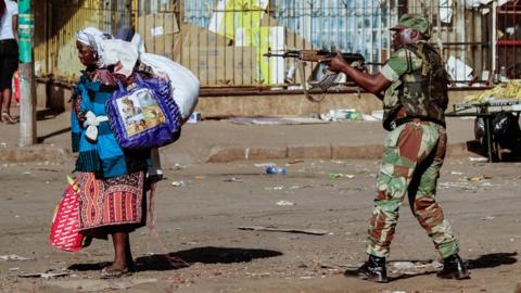 A vendor scurries for cover with her wares as soldiers disperse demonstrators on August 1 2018, in Harare, Zimbabwe