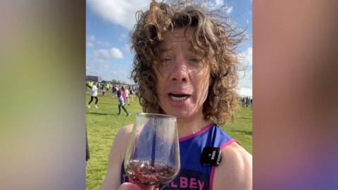 Tom Gilbey holding a glass of wine in his running gear