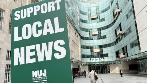 A sign saying 'support local news'