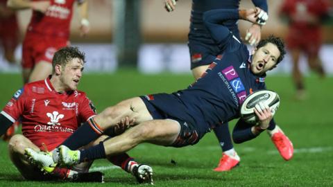 Henry Pyrgos of Edinburgh is tackled by Angus O’Brien of Scarlets