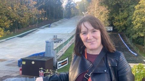 A woman with brown hair standing in front of an artificial ski slope