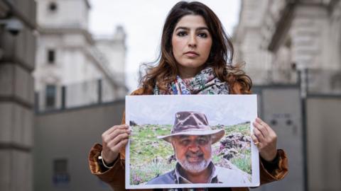 Roxanne Tahbaz holds a photograph of her father, Morad Tahbaz, outside the Foreign, Commonwealth and Development Office