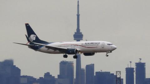 An AeroMexico airplane flies in front of the downtown skyline and CN Tower as it lands at Pearson International Airport on December 10, 2023, in Toronto, Ontario, Canada.