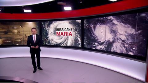 BBC Weather's Matt Taylor stands in the studio in front of a satellite picture of Hurricane Maria