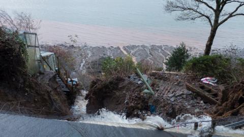 Flood water sweeping away land on the A545 between Menai Bridge and Beaumaris on Anglesey