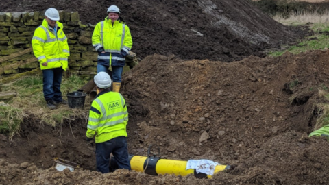 Three engineers repairing damage to a gas pipe