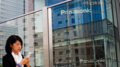 A woman walks past a Panasonic building in Tokyo on May 11, 2017.