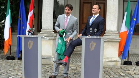 Leo Varadkar shows his socks as Mr Trudeau holds a GAA jersey