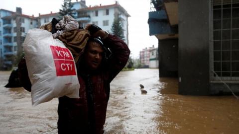 A man carries his belongings towards dry ground in Kathmandu