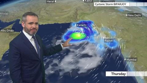 Ben Rich stands in front of a weather map showing the track of Cyclone Storm Biparjoy near India and Pakistan