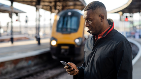 Man on rail platform looks at phone