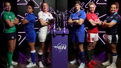 One player from each of the six nations stands with arms crossed around the Women's Six Nations trophy