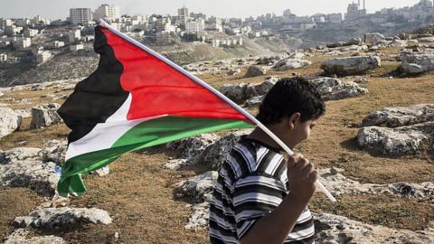 Palestinian boy holds a Palestinian flag.