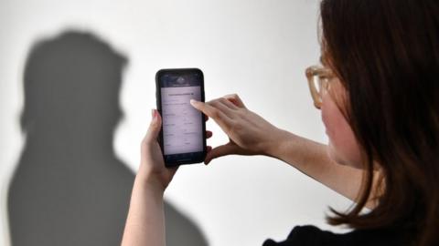 A staged photo of a person using the Australian government's coronavirus tracking app on a phone