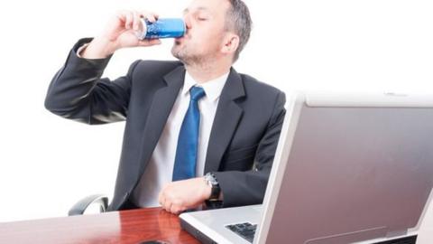 Man at desk drinking energy drink