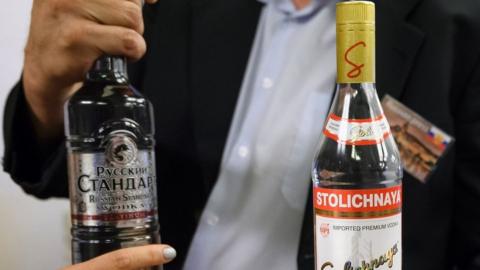 A journalist holds two bottles of vodka that Russian Foreign Minister Sergei Lavrov delivered to waiting journalists after meetings to discuss the Syrian crisis went late into the evening on 9 September 2016, in Geneva.