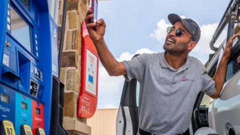 A man sends a picture of gas prices to friends while pumping gas at an Exxon Mobil gas station on June 09, 2022 in Houston, Texas