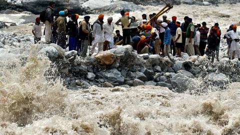 Stranded Indian pilgrims wait to be rescued on the side of a river at Govind Ghat, India, on 23 June 2013