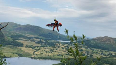 The casualty being winched to a helicopter on a stretcher