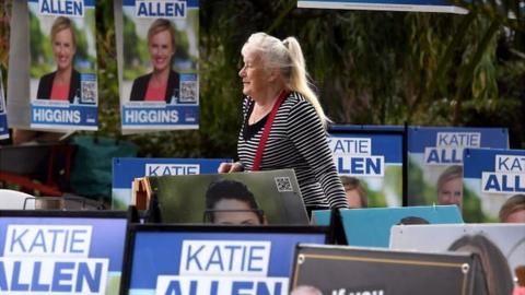 A woman walks past candidate placards outside a polling centre