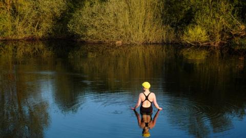 A woman entering a river in her swimsuit
