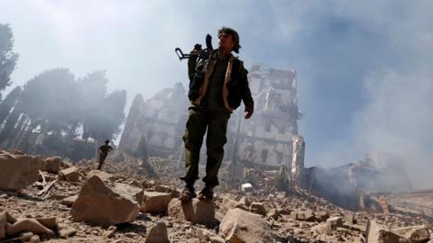 Houthi rebel fighters stand outside a presidential palace destroyed in a reported Saudi-led coalition air strike in Sanaa, Yemen (5 December 2017)