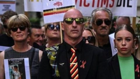 photo of protestors holding placards with messages related to the NHS infected blood scandal