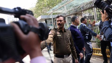 Police officers stand outside a building having BBC offices, where income tax officials are conducting a search, in New Delhi, India