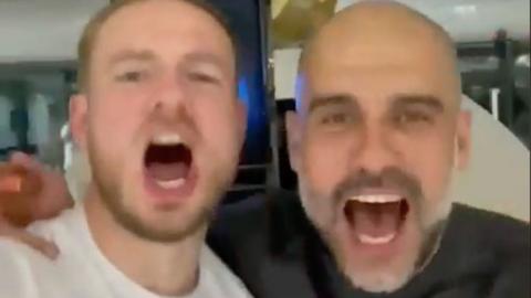 Pep Guardiola and a member of Manchester City staff sing.