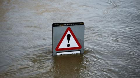 A traffic warning sign peeks out above flood waters in Shrewsbury, Shropshire, in central England on February 26, 2020