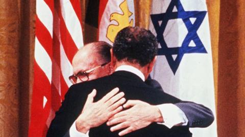 Israel's Menachem Begin and Egypt's Anwar Sadat (from behind) hug (18 Sept 1978)