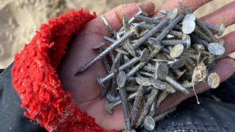 A pile of metal nails in a woman's hand