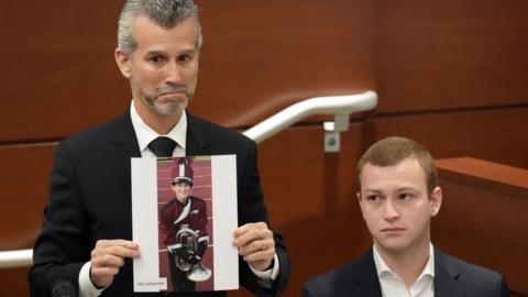 A man in court holds a photo of his son who was among those killed in a 2018 Parkland high school shooting.