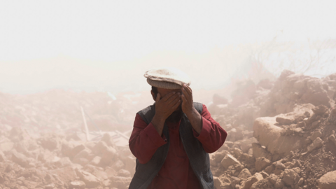An Afghan man covers his face amid the dust after the recent earthquake, in the district of Zindajan, in Herat, Afghanistan October 10, 2023