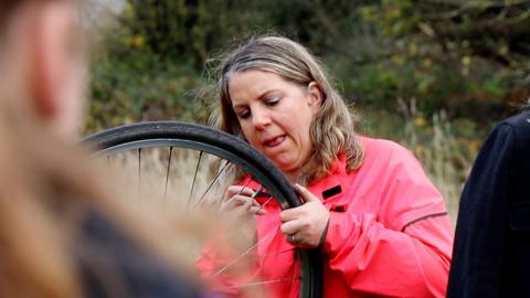 A woman repairing a bike puncture