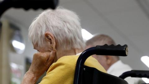 An elderly woman sits in a wheelchair