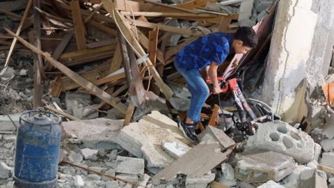 A Palestinian boy pulls a bicycle from rubble at a house damaged during an Israeli raid, in Balata camp, Nablus, in the occupied West Bank (22 May 2023)