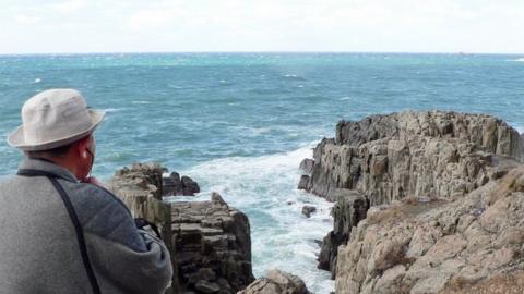 Former police officer Yukio Shige stands near the cliffs of Tojinbo, looking out to sea with a pair of binocular in hand. Fukui prefecture, northern Japan, 23 December 2008.