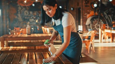 Woman cleaning table in restaurant
