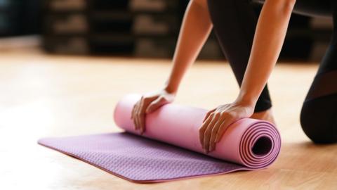 A woman rolls a yoga mat