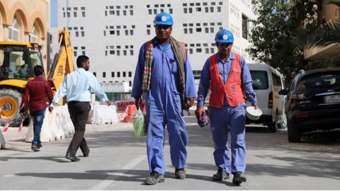 Migrant workers walk next to a construction site in Doha, Qatar (6 December 2016)