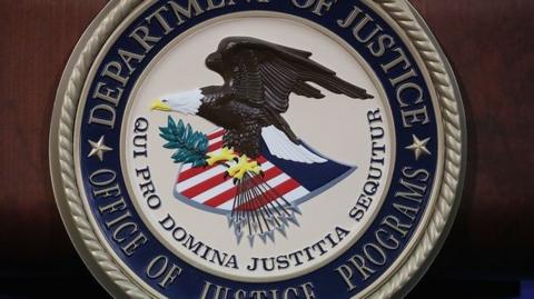 The US Department of Justice seal is seen on a lectern.